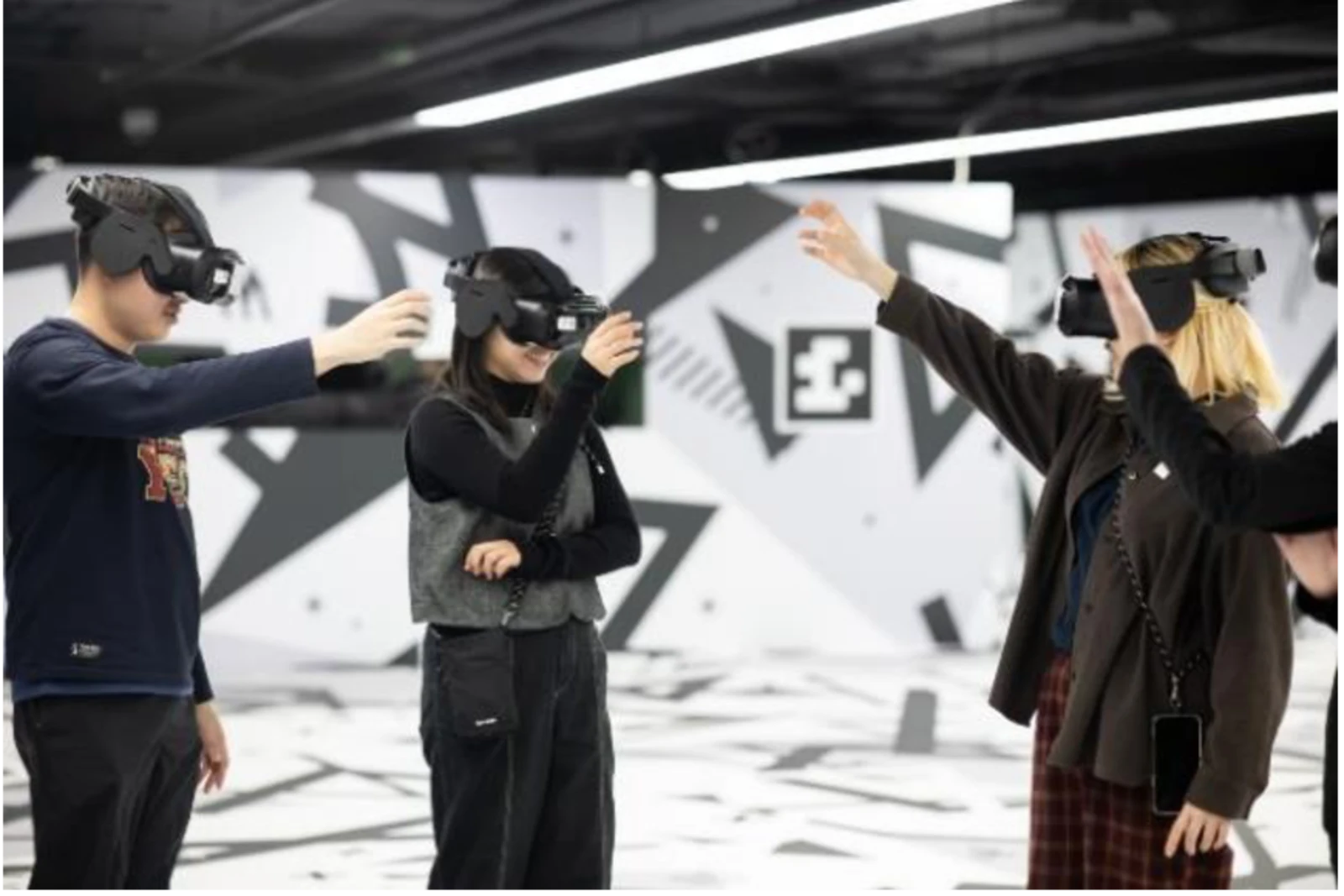 HKDI Galleryの会場でVRヘッドセットを装着し、手を伸ばして体験する3人の来場者