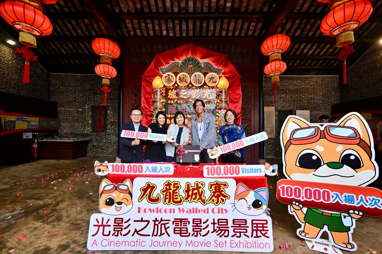 九龍寨城公園の映画セット展会場で、赤い提灯と展示看板の前に立つ関係者